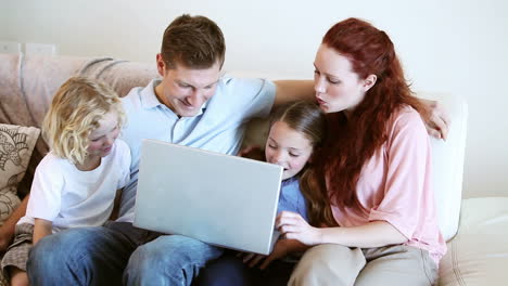 Familia-Sonriente-Mirando-Una-Computadora-Portátil