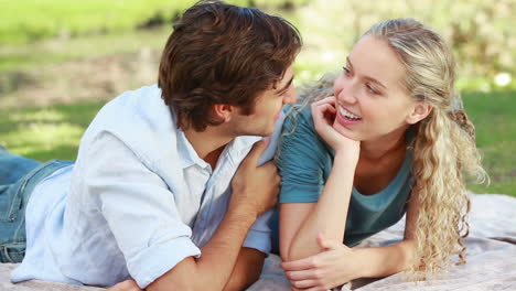 A-couple-lying-on-the-ground-share-a-kiss-and-then-look-at-the-camera