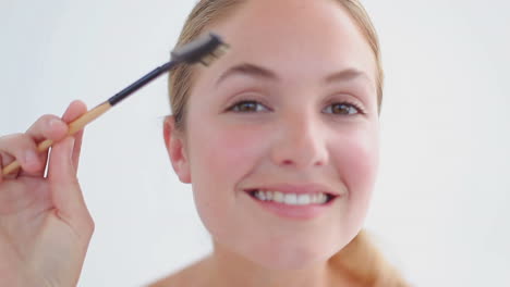 Smiling-woman-attentively-brushing-her-eyebrows