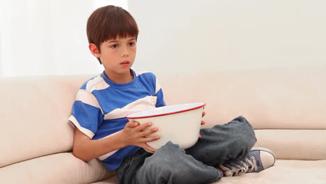 Boy-hiding-behind-his-bowl-of-popcorn-as-he-gets-scared-by-a-movie-scene