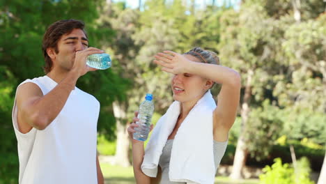 Una-Pareja-Toma-Un-Descanso-Del-Entrenamiento-Mientras-Bebe-Agua-Y-Charla