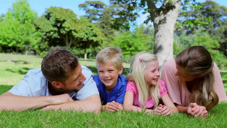 Familia-Tumbada-En-El-Césped-Juntos-Antes-De-Mirar-Hacia-Arriba-Y-Reír