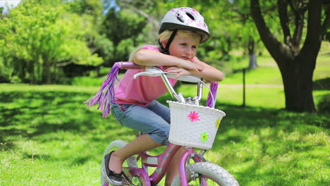 Ein-Mädchen-Sitzt-Auf-Einem-Fahrrad-Und-Lehnt-Sich-Auf-Den-Lenker,-Während-Die-Quasten-Im-Wind-Wehen
