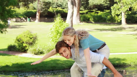 A-man-gives-his-girlfriend-a-piggyback-as-they-look-at-the-camera