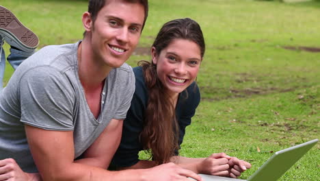 Two-friends-laughing-as-the-look-at-a-laptop-while-lying-next-to-each-other