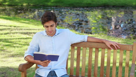 Man-sits-on-a-bench-while-reading-a-book