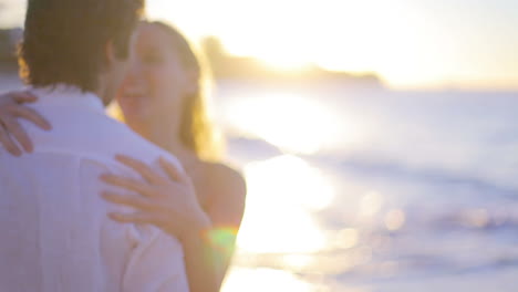 Couple-turning-and-kissing-during-sunset-before-they-walk-towards-the-sea