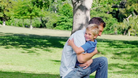 El-Padre-Se-Arrodilla-En-El-Césped-Antes-De-Abrazar-A-Su-Hijo,-Que-Corre-Hacia-él.