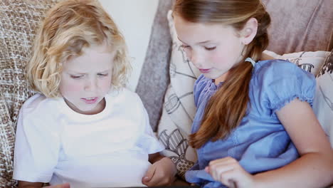 Siblings-sitting-on-the-couch-while-using-a-tablet-computer