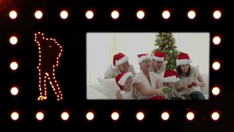 Silhouette-of-a-man-dancing-while-a-video-appears-showing-a-family-wearing-Santa-hats