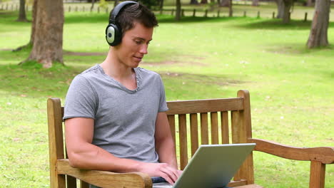 Camera-rises-to-show-a-man-typing-on-a-laptop-while-wearing-headphone