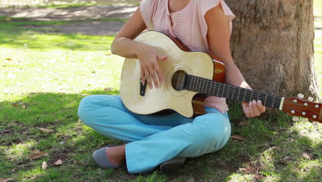 Die-Kamera-Fährt-Hoch-Und-Zeigt-Ein-Mädchen,-Das-Im-Park-Gitarre-Spielt