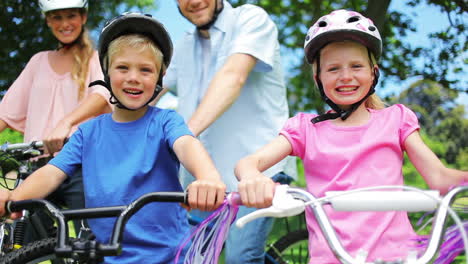 Die-Familie-Genießt-Eine-Radtour-Im-Park,-Winkt-Und-Lächelt.