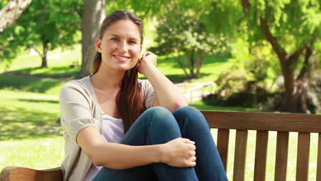 Mujer-Sonriente-Sentada-En-Un-Banco-