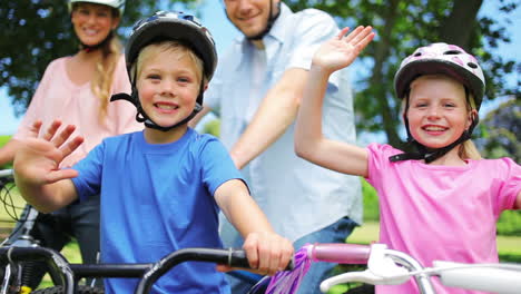 La-Cámara-Se-Eleva-Para-Mostrar-A-Una-Familia-Sentada-En-Bicicleta-Mientras-Los-Niños-Saludan-Mientras-Sonríen.