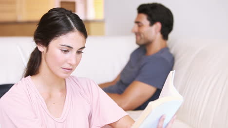 Mujer-Joven-Leyendo-Un-Libro-Delante-De-Su-Novio.