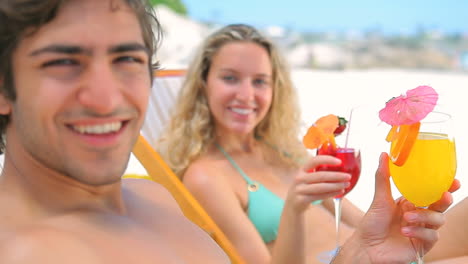 Couple-sitting-on-deck-chairs-with-cocktail