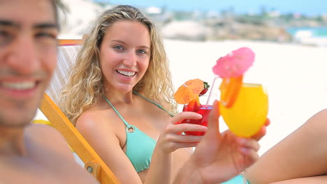 Couple-sitting-on-deck-chairs-toasting