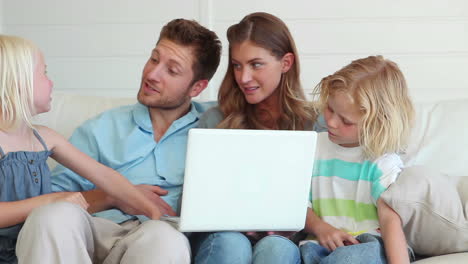 Family-sitting-together-while-using-a-laptop