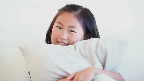 Niña-Sentada-En-El-Sofá-Con-Una-Almohada