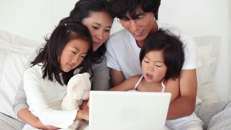 Family-sitting-together-as-they-use-a-laptop