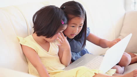 Two-girls-sitting-together-while-using-a-laptop