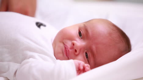 New-born-baby-laying-on-a-bed-with-the-hand-of-an-adult