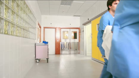 Medical-team-wheeling-the-bed-of-a-patient-in-a-hallway