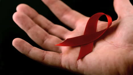 AIDS-Symbol-Mit-Roter-Schleife-Fällt-über-Die-Hand-Eines-Mannes-