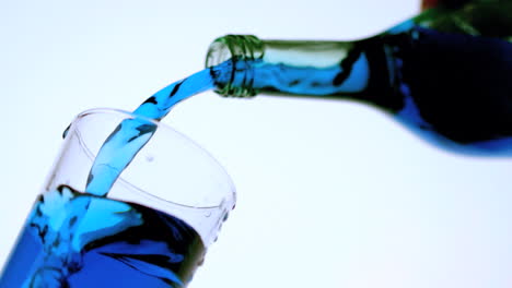 Blue-liquid-pouring-into-glass-low-angle-close-up