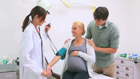 Doctor-measuring-the-blood-pressure-of-a-pregnant-patient-with-her-husband