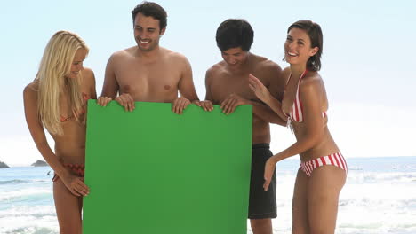 Friends-holding-a-green-board-on-the-beach