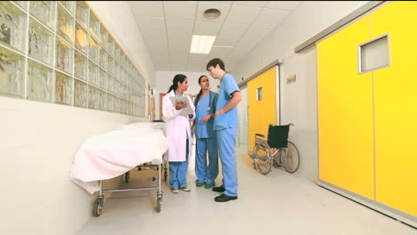 Female-doctor-talking-to-male-and-female-nurses-in-a-hallway