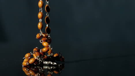 Rosary-beads-falling-onto-black-surface