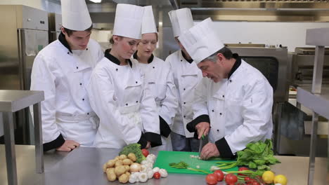 Cocineros-Mirando-Al-Jefe-De-Cocina-Cortando-Verduras