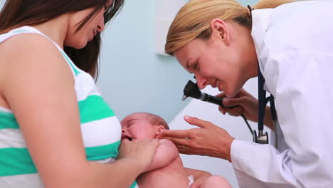 Mother-holding-a-baby-in-an-examination-room-with-a-female-doctor