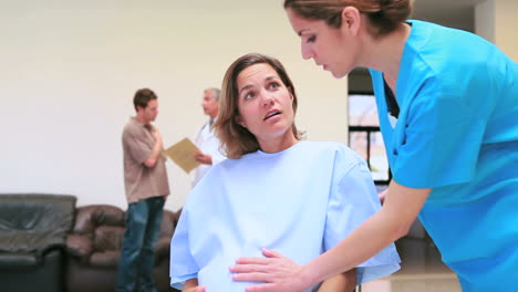 Nurse-supervising-pregnant-woman-while-doctor-speaking-with-man