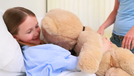 Glückliche-Frau-Gibt-Einem-Mädchen-Im-Bett-Einen-Teddybär