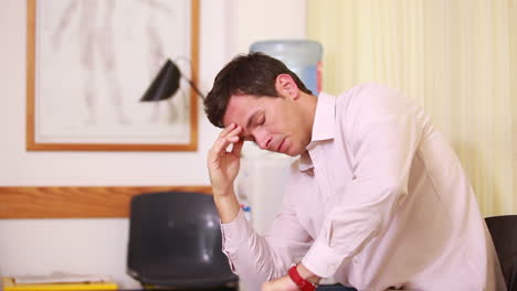 Man-holding-his-head-while-sitting-in-a-waiting-room