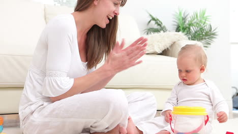 Baby-putting-a-green-dice-into-bucket-and-woman-applauds