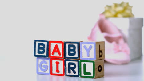 Baby-girl-blocks-sliding-across-with-booties-and-gift-box-in-background