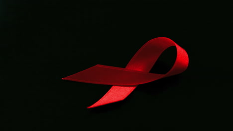 Red-ribbon-dropping-down-on-black-background