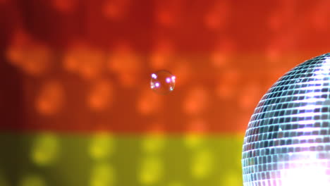 Glänzende-Rotierende-Discokugel-Mit-Schwebenden-Blasen-Vor-Regenbogenfahne
