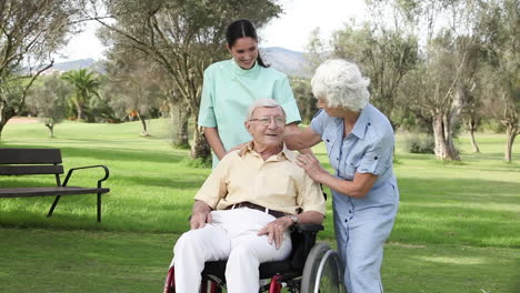 Woman-and-nurse-talking-to-man-in-wheelchair
