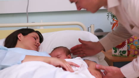 Padre-Feliz-Mirando-A-Su-Esposa-Y-A-Un-Bebé-Recién-Nacido-Durmiendo