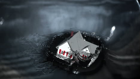 Miniature-model-house-falling-into-grey-water