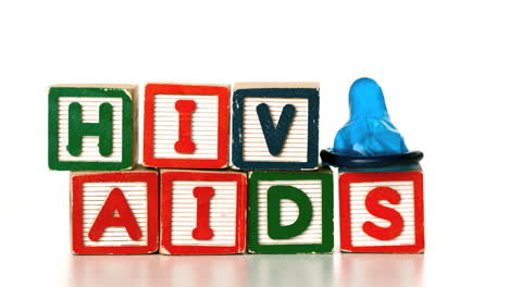 Blue-condom-falling-on-blocks-spelling-AIDS-and-HIV