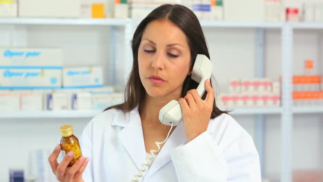 Farmacéutica-Llamando-Mientras-Sostiene-Una-Botella-De-Medicamento