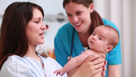 Doctor-Con-Una-Madre-Sonriente-Sosteniendo-A-Un-Bebé