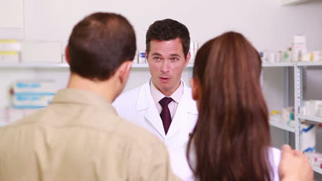 Pharmacist-presenting-a-flask-of-pills-to-a-couple